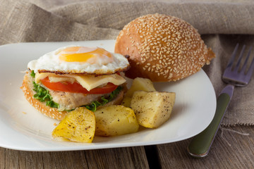 Cheeseburger with fried egg and potato wedges