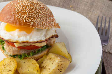 Cheeseburger with fried egg and potato wedges