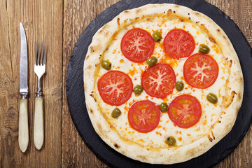 Pizza vegetarian on plate on stone black try with fresh tomatoes