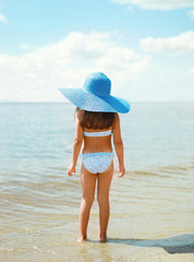 Summer travel photo pretty little girl in straw hat on the beach