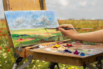 artist hand painting with brush  in the meadows