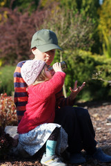 Two-year girl with her brother in the garden