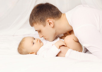 Father and baby at home lying on the bed together, bedtime