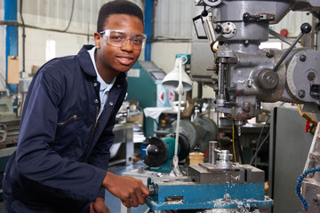 Male Apprentice Engineer Working On Drill In Factory