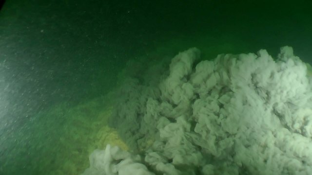 Underwater avalanche on a rocky slope, follow shot.
