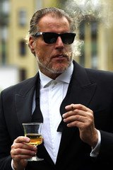 Mann im Smoking mit Glas und Zigarette