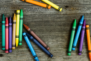 crayons on old rustic wooden background - top view