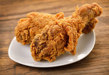 fried chicken on a white plate set on a wood