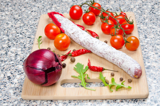 Smoked sausage, tomatoes and onion on a wooden board