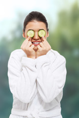 Woman in bathrobe with cucumber.