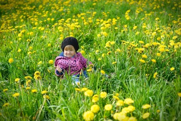 Young girl on green meadow full of yellow flowers.