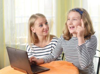 Happy girl and grandmother using a laptop in home.