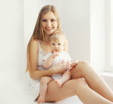 Happy young mother and baby at home in white room