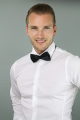 handsome man wearing a bow tie over a grey background