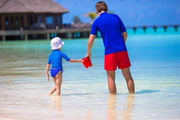 Fototapeta na wymiar Happy father and little daughter have fun on tropical beach