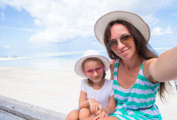 Fototapeta na wymiar Mother and little girl taking selfie at tropical beach