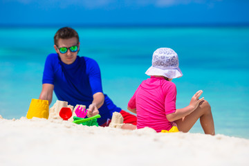 Adorable little girl and happy father playing with beach toys on