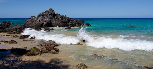 Surf around rocks of Puako beach