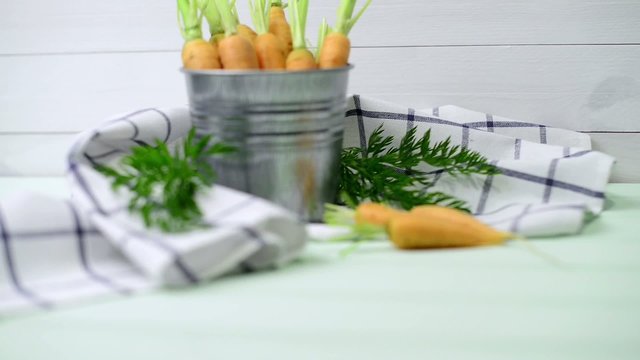 Carrots inside a metal bucket on the light green wooden table.