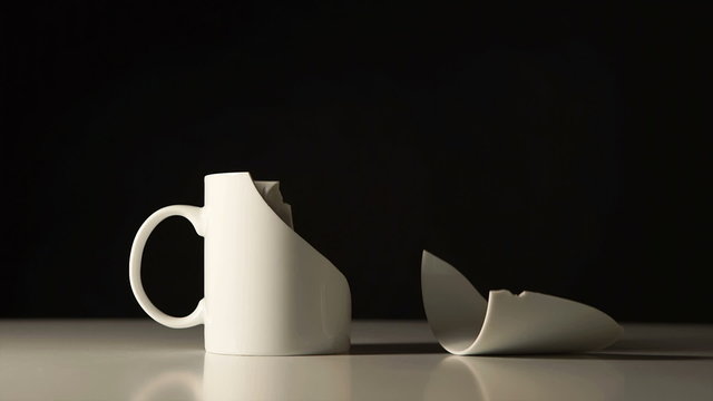 Broken White mug and splinter beside her
