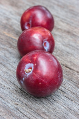 Fresh plum in a row on wooden background ,select focus.