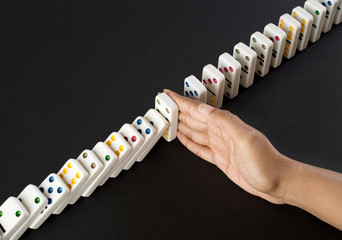 Hand stopping falling dominoes - domino effect