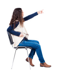 back view of young beautiful  woman sitting on chair and pointin