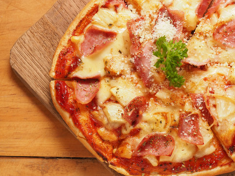 Hawaiian pizza on wood plate