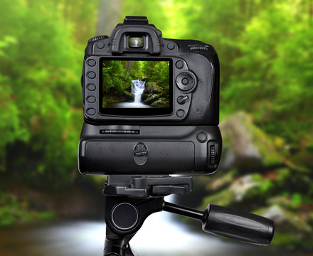 Dslr camera on tripod photographing waterfall