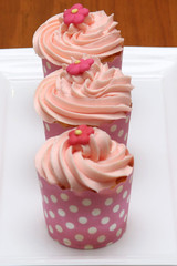 three pink cupcakes on white plate