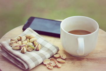 Pistachio nut and white coffee cup on wood background.