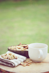 Pistachio nut and white coffee cup on wood background.