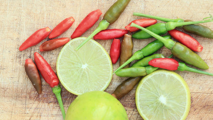 Slice lemon and chili on wood background.