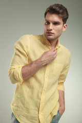 Attractive young business man closing his yellow shirt.