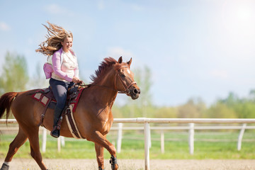 girl riding her brown horse in a training field