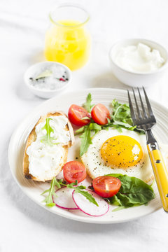 fried egg with tomatoes, arugula, radish, and toast with cheese 