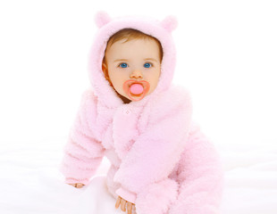 Portrait of sweet baby with pacifier in soft overalls on a white
