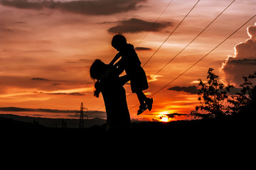 silhouette of mother playing with her son