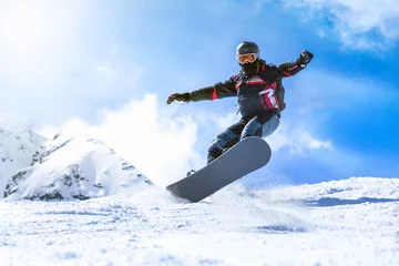 Abwaschbare Fototapete Wintersport Snowboarder im Winter vom Hügel springen