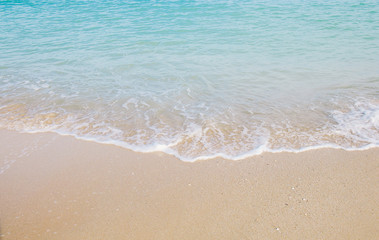Fototapeta na wymiar Soft blue wave roll into sandy beach, texture background