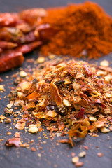 Sliced, dried, red chili peppers and seeds on a stones background