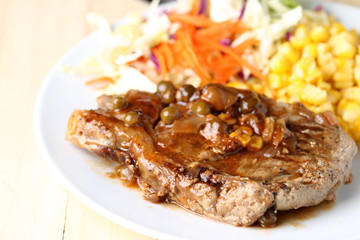 Beef Steak on white dish, plank wood background.