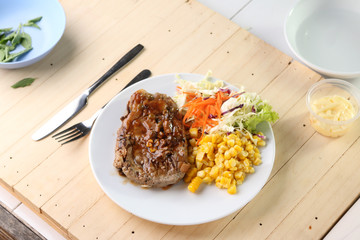 Beef Steak on white dish, plank wood background.