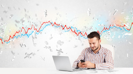 Business man sitting at table with stock market graph