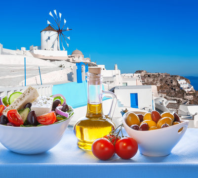 Fototapeta Greek salad against windmill in Santorini island, Greece