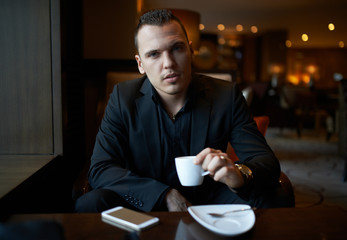 cheerful businessman drinking coffee in restaurant