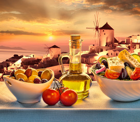 Greek salad against windmill in  Santorini island in Greece