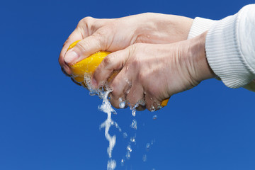 Hands squeeze wet fabric against blue sky.