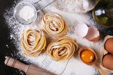 Raw homemade pasta and ingredients for pasta on wooden background