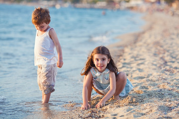 Two cute little children playing on the beach